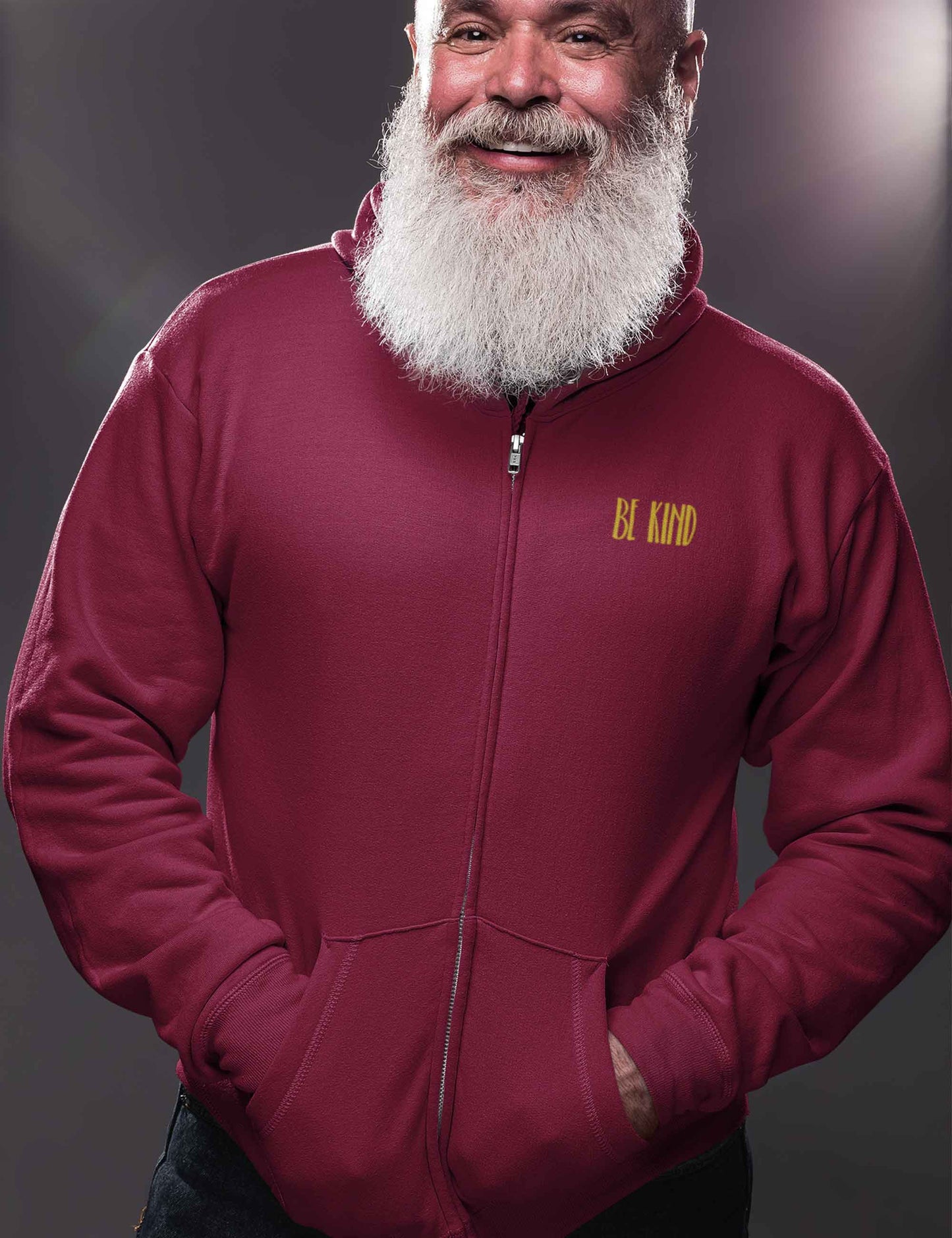 Mann mit weißem Bart und Zip-Hoodie in einem beerigen Rotton mit weichem Schriftzug aus Flock: be kind
