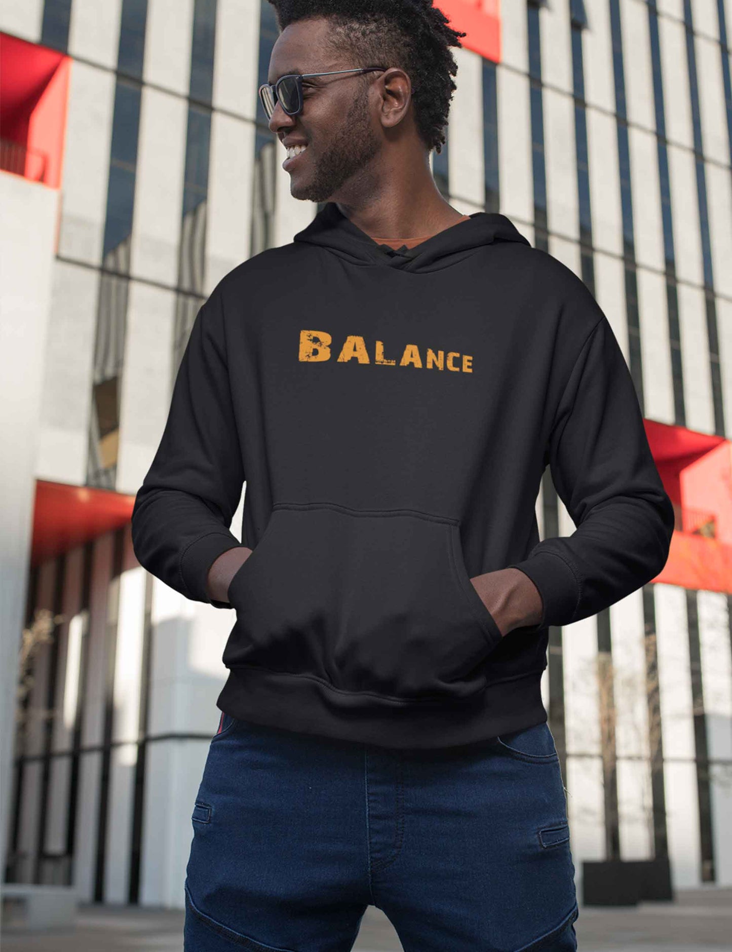 Mann mit schwarzem Hoodie mit orange farbenem Schriftzug BALANCE