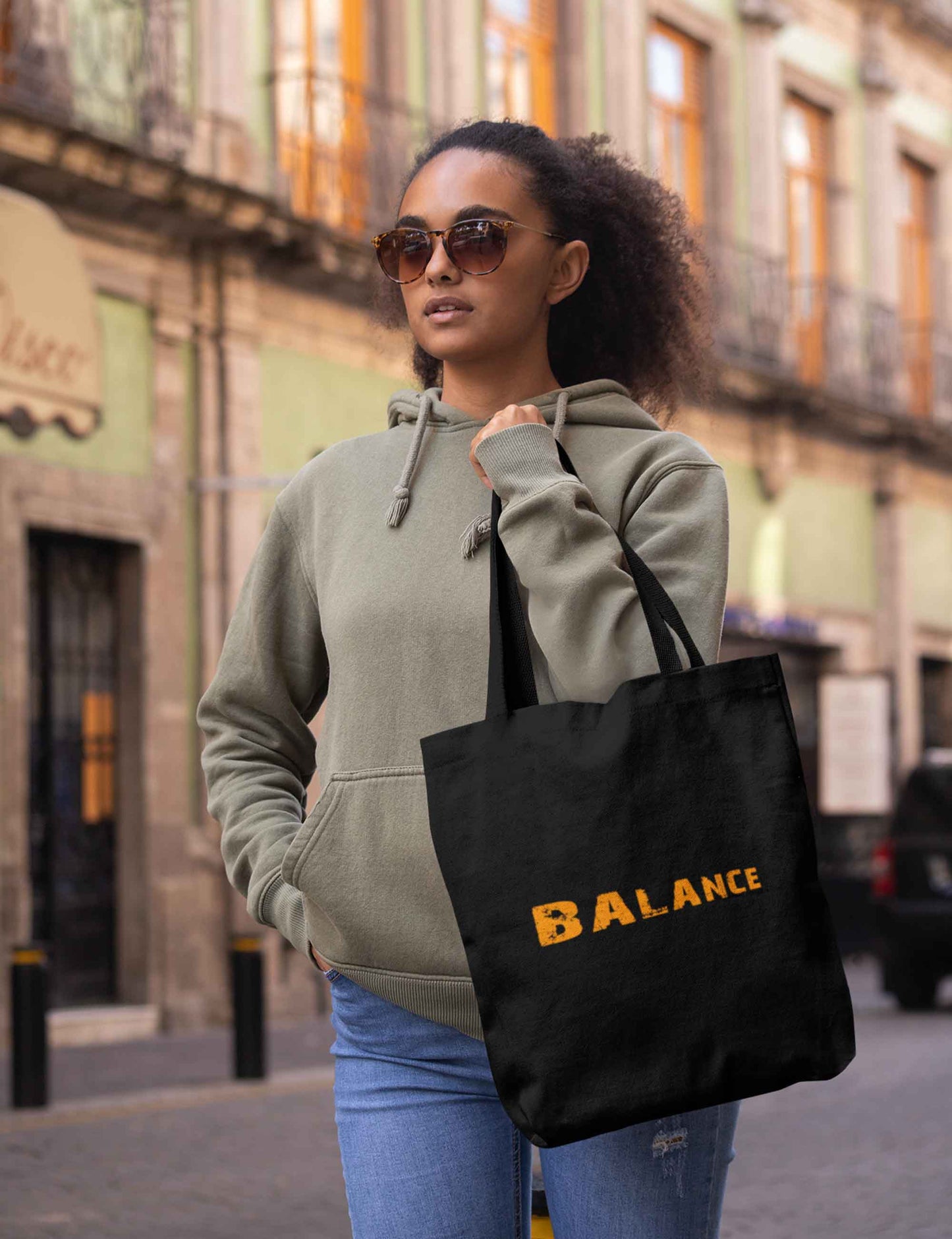 Frau mit Einkaufsbeutel in Schwarz mit der Aufschrift Balance in orange