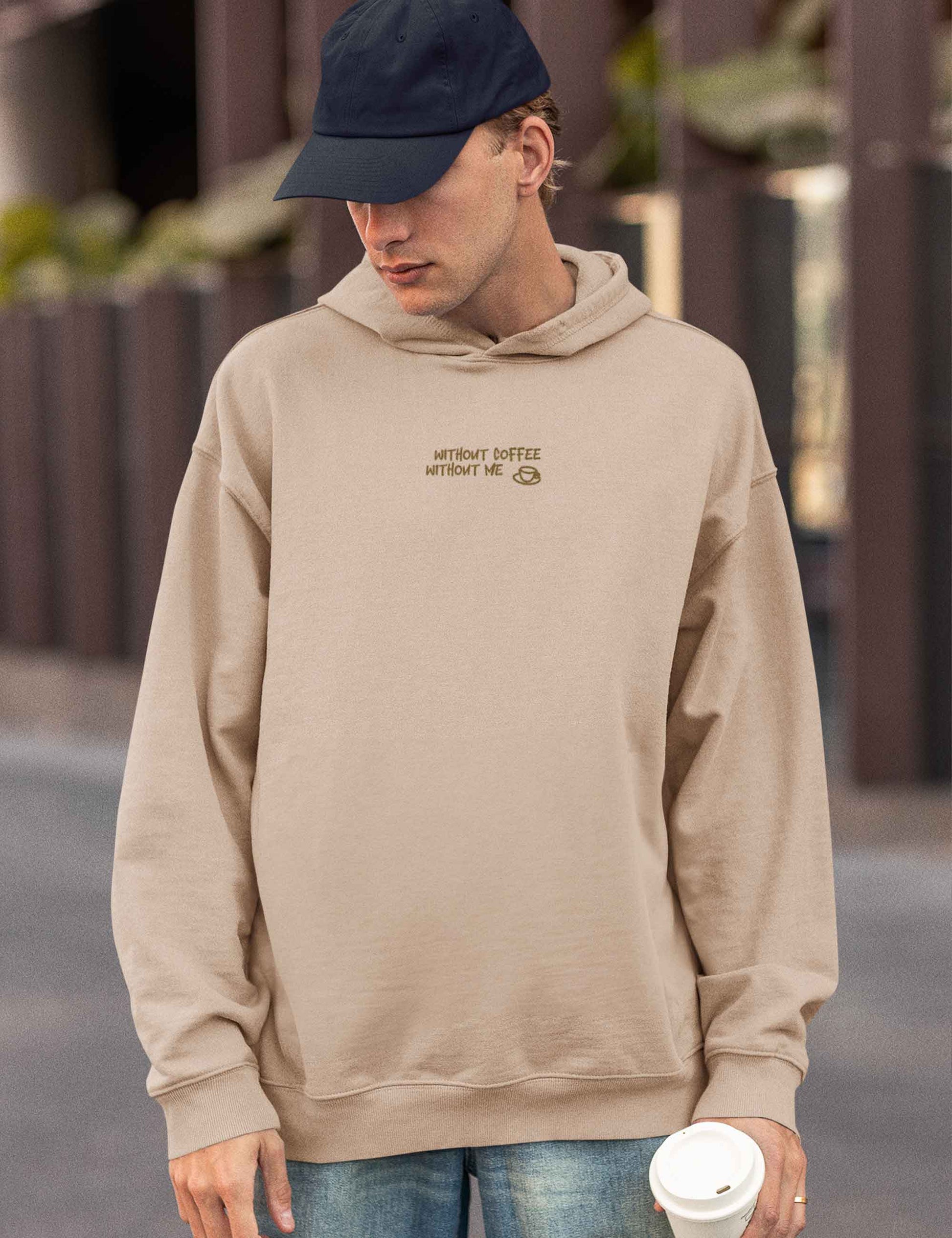 Mann trägt einen sandfarbenen oversized Hoodie mit dem Aufdruck: without coffee, without me.