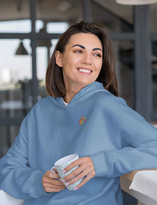 Frau trägt einen Oversized geschnittenen, kuscheligen Hoodie in einem tollen Graublau - und mit bunten Lolli als Hingucker