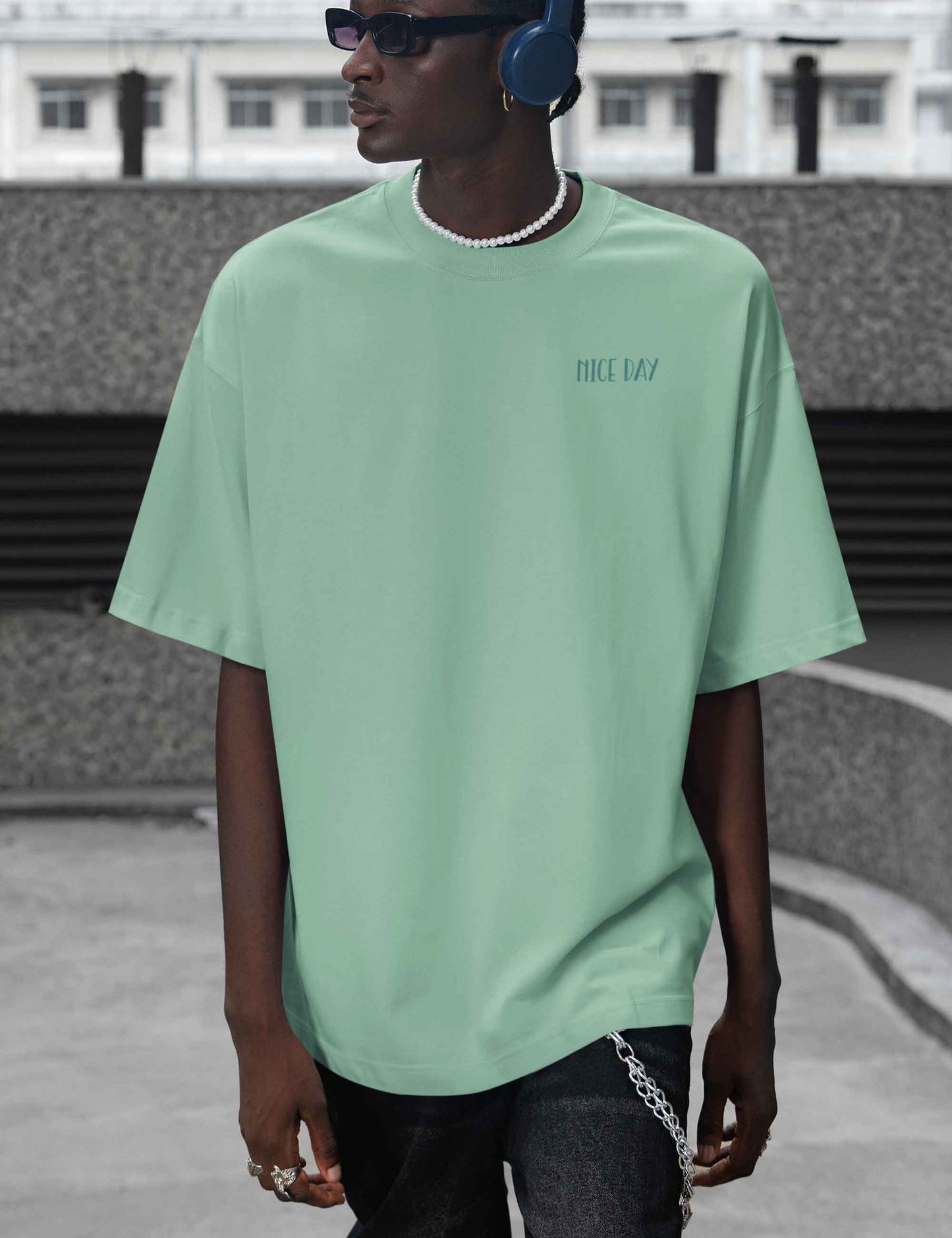 Junger Man mit lässigem oversized T-Shirt in mint mit NICE DAY Print vorne 