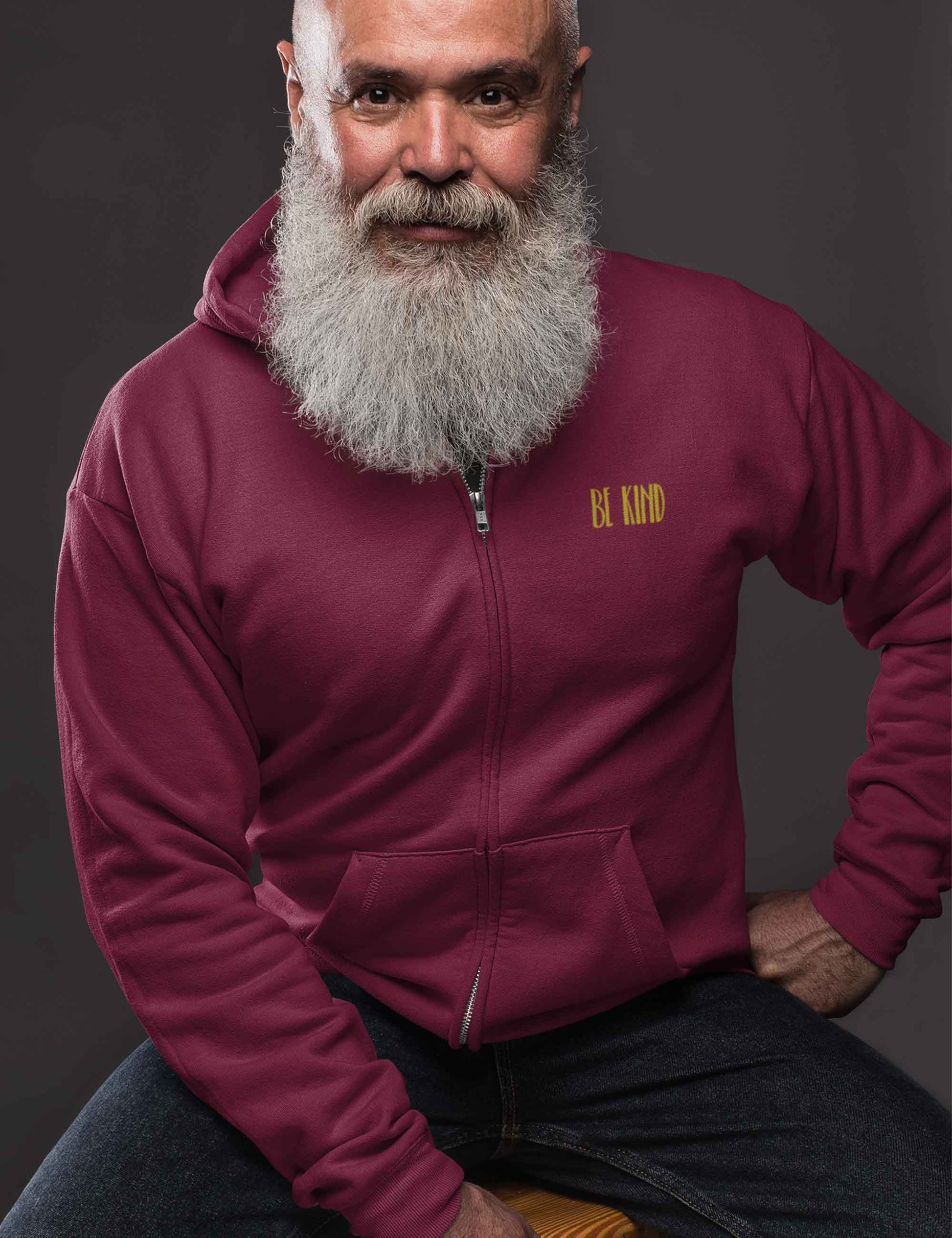 Mann mit weißem Bart und Zip-Hoodie in einem beerigen Rotton mit weichem Schriftzug aus Flock: be kind