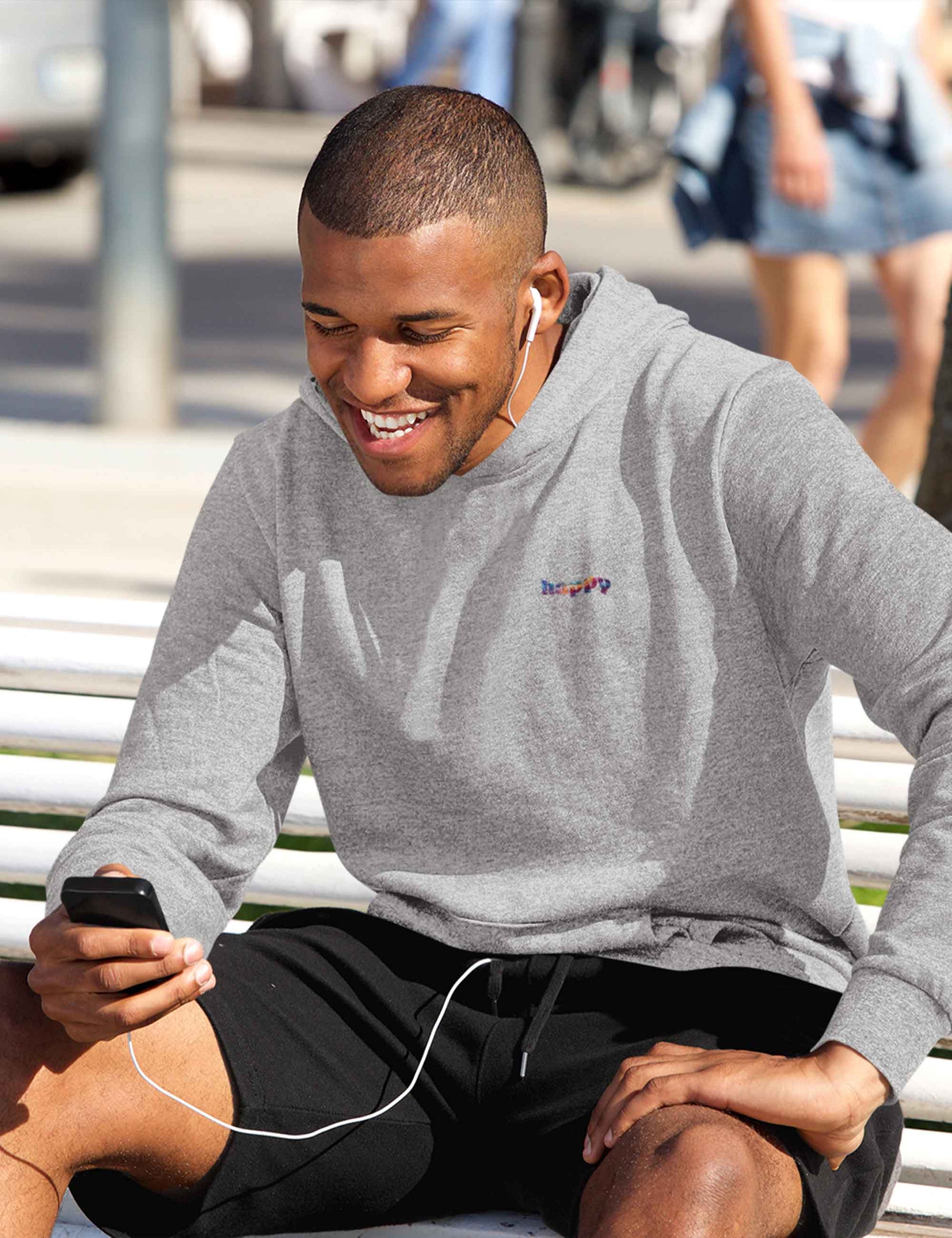 Lachender Mann mit grau meliertem Hoodie mit kleinem happy in bunten Farben auf der Front
