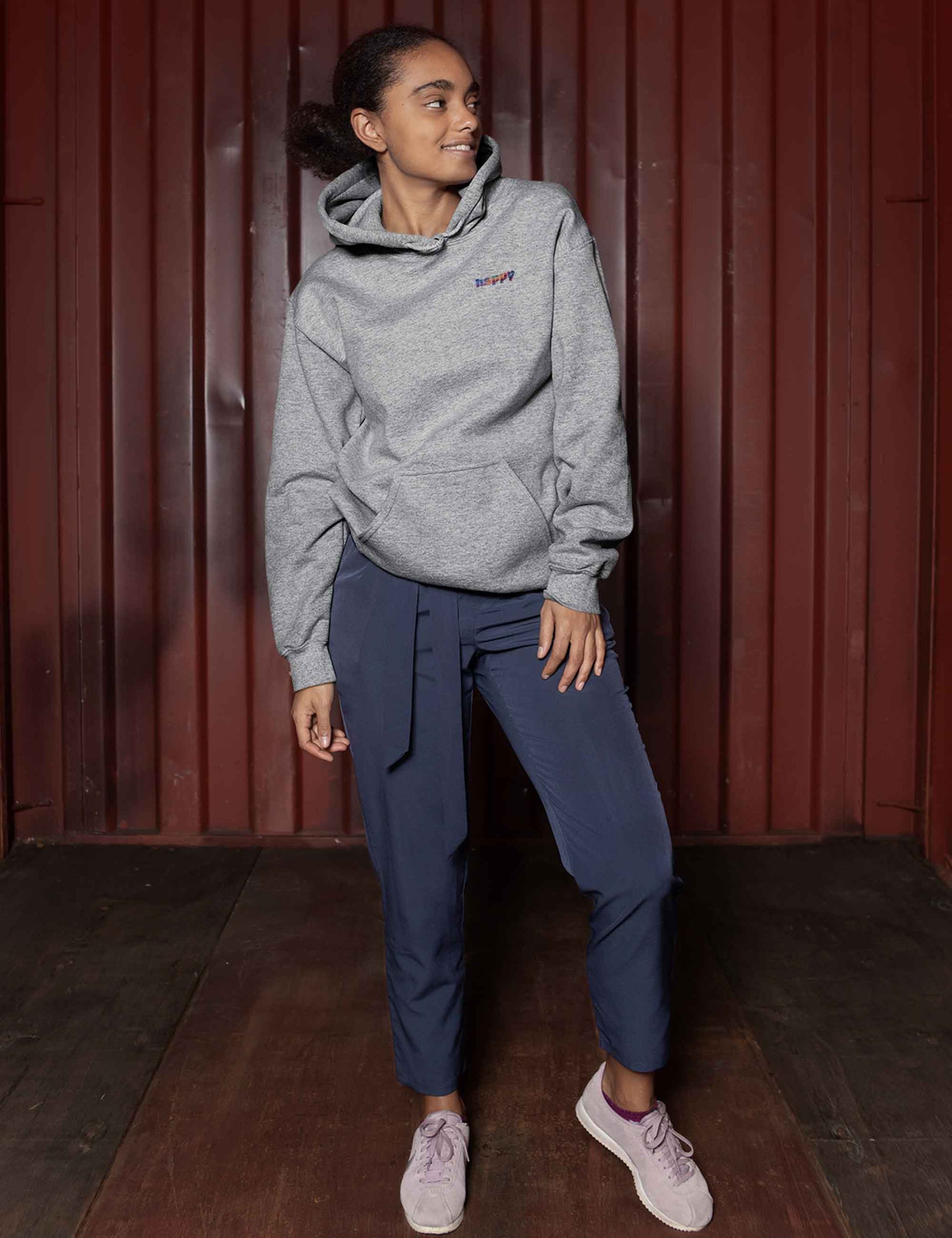 Lächelnde Frau mit grau meliertem Hoodie mit kleinem happy in bunten Farben auf der Front